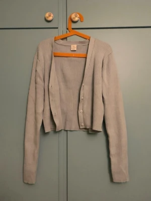 Ljusblå ribbad kofta från Lindex - Säljer en ljusblå ribbad kofta från Lindex med långa ärmar och knäppning framtill. Koftan är i ett mjukt och stretchigt material och har en klassisk, enkel design som passar till mycket.