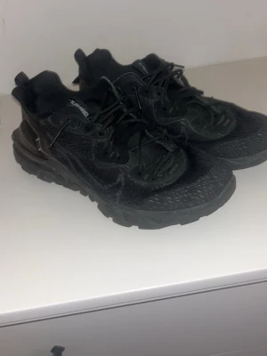 Svarta Nike sneakers med mesh - Snygga helsvarta Nike sneakers med sportig design och robust sula. Ovandelen är i mesh och syntetmaterial för bra andningsförmåga. Skorna har snörning och diskret Nike-logga på sidan. Perfekta för en streetwear-look.