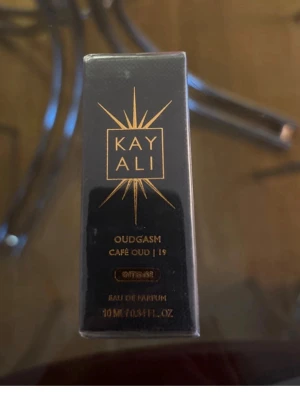 Kayali Oudgasm Café Oud EdP 10ml - Kayali Oudgasm Café Oud | 19 Eau de Parfum i en elegant svart och guld förpackning. Doften kombinerar oud och kaffe för en unik, lyxig parfymupplevelse. Flaskan rymmer 10 ml och är perfekt att ha med sig i väskan.