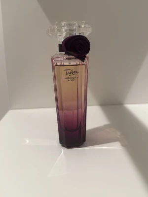 Tresor midnight rose - Trésor Midnight Rose, EdP från Lancome är en förförisk parfym med romantiska toner och passionerade ackord. Sofistikerad, elegant och lockande sensuell.  Doftfamilj – Blommig/Trä mysk Toppnoter – Hallon och ros Mellannoter – Jasmin, pion, rosépeppar och vinbärsknoppar Basnoter – Mysk, vanilj och ceder från Virginia
