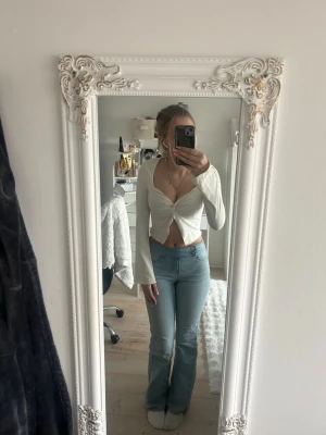 Vit croppad omlottopp från Shein - Säljer en vit croppad topp från Shein med omlott-design och snörning framtill. Toppen har långärmade ärmar och en v-ringad hals. Materialet är mjukt och stretchigt, perfekt för att skapa en snygg och trendig look.