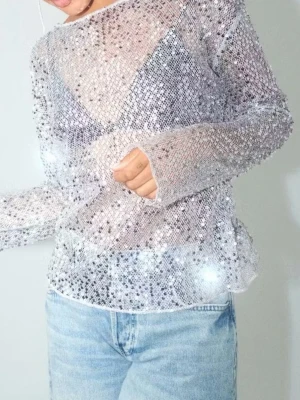 Glittrig silver topp med paljetter - Säljer en glittrig långärmad topp i silver med täckande paljetter över hela plagget. Toppen har en rund halsringning och är lätt genomskinlig. Passar snyggt till både jeans och kjol för en trendig look.