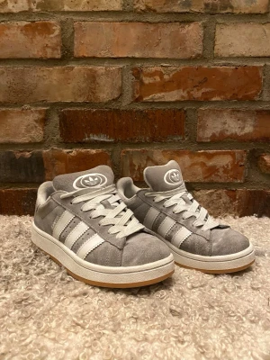 Grå Adidas Campus sneakers - Säljer dessa väldigt fina Adidas Campus i storlek 37 och 1/3. Skorna är sparsamt använda och defekt ser du på sista bild. Skick ca 8/10, nypris≈ 1449, mitt pris= 449🔥Bara att höra av dig vid funderingar👑