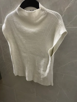 Vit ribbstickad topp från NA-KD - Säljer en stilren vit ribbstickad topp från NA-KD. Toppen har en rak passform och är gjord i mjukt stickat material, perfekt för lager på lager eller som den är. Enkel men trendig design som passar till mycket.