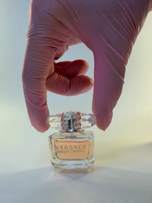 Versace Bright Crystal parfym - Versace Bright Crystal parfym i en genomskinlig glasflaska med ljusrosa doftvätska. Flaskan har en exklusiv, kristalliknande kork och elegant etikett framtill. Perfekt för dig som gillar lyxiga och fräscha dofter.