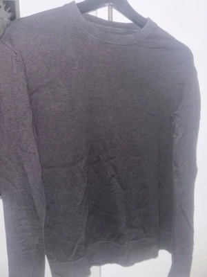 Mörkgrå tröja These Glory Days - En stilren mörkgrå tröja från These Glory Days i mjukt material. Tröjan har rund halsringning, långa ärmar och ribbade muddar vid ärmslut och nederkant. Perfekt för en clean och enkel look. Använd fåtalet gånger storlek M