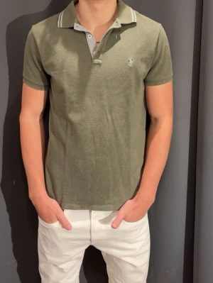 Ralph Lauren Pike - Tja, säljer en grön Ralph Lauren pike. Storlek M. Skick 10/10, aldrig använd. Nypris 2500, mitt pris 529. Perfekt inför sommar och vår! SÅKLART ÄKTA!  Hör av dig vid frågor o funderingar!