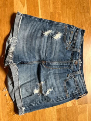 Högmidjade hollister jeansshorts - Hödmidjade jeansshorts från hollister. Strl 24.  Midjemått tvärsöver ca 29 cm enligt bild. 