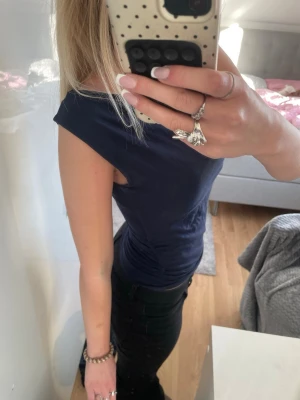 Mörkblå ärmlös topp - Snygg mörkblå ärmlös topp med skrunch i midjan. Perfekt att styla med jeans eller kjol för en clean och enkel look. Mjuk och stretchig känsla i materialet.