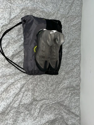 Nike fotbollsskor  - Säljer ett par grå Nike fotbollsskor som jag tagit ut snörena på men ja kan sätta i dem igen. De har en liten skada uppepå strumpan, ett litet hål det är det ända. Inget fel på skorna annars. Det är också gräsdobbar.