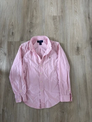 Ralph Lauren skjorta - Ralph Lauren skjorta i mycket bra skick, inga defekter! Storlek 16 vilket motsvarar XS och passar bra på dig som är mellan 160-165. Om ni har frågor eller funderingar är det bara att höra av sig 🙌  Bra att veta:  - Jag gör ej returer!   Se mått nedan:  Längd: 63 cm  Bred: 46 cm  Ärm: 51 cm