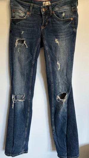 Blå slitna jeans - Slitna jeans som är pefekta! Storlek: 36 mått: midjemått rakt över ca 35 cm Innerbenslängd: 76 cm (jeansen passar ej modellen därav bilderna)