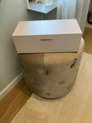 Rosa smyckeskrin med fack - Ljusrosa smyckeskrin med flera fack från Edblad.  Utsidan är slät med ett silverfärgat handtag och insidan är klädd i mjukt grått tyg. Perfekt för att organisera ringar, örhängen, armband och halsband. Köpt från butiken förra året. Storlek: 29,5 cm lång, 14,5 cm djup och 10 cm hög. Väl omhändertaget i stort men tecken användning finns särskilt där ringar/örhängen placerats, som syns på bilderna. 