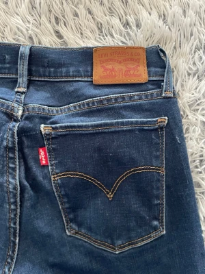 Levi's 710 Super Skinny jeans blå - Säljer ett par mörkblå Levi's 710 Super Skinny jeans med klassisk femficksdesign och snygga kontrastsömmar. Jeansen har en tajt passform och är tillverkade i stretchigt denim för en bekväm känsla. Perfekta för dig som gillar en slimmad look.