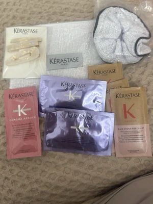 Kérastase hårvårdsprover & accessoarer - Paket med flera Kérastase hårvårdsprover i olika serier som Chroma Absolu, Blond Absolu och Genesis. Inkluderar även två hårklämmor i beige med pärldetaljer och en vit scrunchie. Perfekt för dig som vill testa olika produkter från Kérastase.