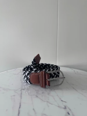 Svart grå vit flätat bälte - Tja det är helt nytt och är ca 105cm långt och 3,5cm brett. Det är i elastiskt material och en massa andra färger finns i min profil.
