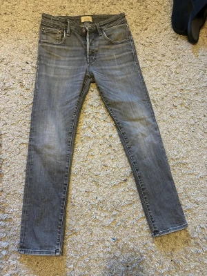 Jack and jones - Snygga grå slim fit jeans med klassisk femficksdesign och diskreta slitningar. Jeansen har raka ben och normal midja. Perfekta för en avslappnad och trendig look. Materialet är troligtvis bomull med lite stretch för extra komfort.