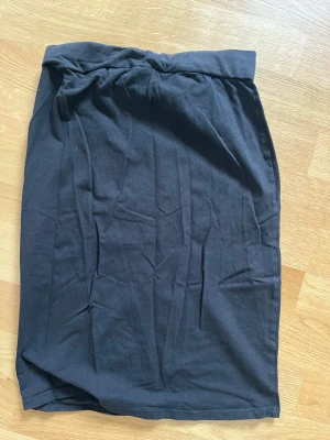 Svart midilång kjol från 157 - En svart, enkel och rak kjol från 157 i mjukt bomullsmaterial. Kjolen har resår i midjan och är midilång, vilket gör den lätt att styla med olika toppar. Perfekt för dig som gillar en clean och basic look.