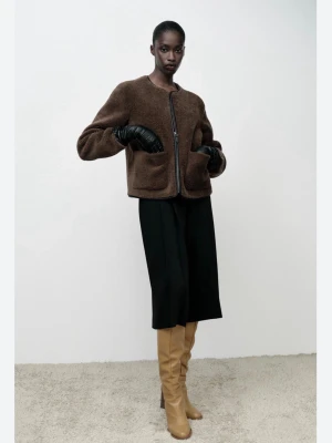 Brun teddyjacka från ZARA - Mysig brun teddyjacka från ZARA med rund halsringning och dragkedja framtill. Jackan har två stora fickor fram och är tillverkad i ett fluffigt teddy-material som ger en trendig och avslappnad look. Perfekt för att hålla värmen under kyliga dagar.