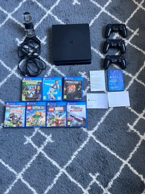 PlayStation 4 Slim med spel och tillbehör - Säljer en svart PlayStation 4 Slim med tre svarta handkontroller, laddstation, kablar och sju PS4-spel: FIFA 19, Minecraft, Crash Bandicoot, LEGO Worlds, LEGO Marvel Super Heroes, Little Big Planet 3 och Need for Speed Rivals. Perfekt för gamingkvällar med vänner! Controllers funkar bra men can vara lite konstigt ps4 är 4 år gammal 