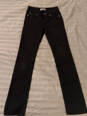 Acne svarta jeans 26/32 - Säljer ett par svarta jeans från Acne med raka ben och klassisk femficksdesign. Jeansen är tillverkade i en mix av bomull och polyester och har en snygg, stilren look som passar perfekt till många outfits 🌸