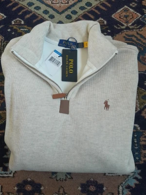 Ralph Lauren Halfzip - Snygg Ralph Lauren med klassisk broderad logga på bröstet och ribbade muddar. Perfekt för lager-på-lager och har en stilren look med diskreta detaljer. Riktigt mjuk och varm insida, perfekt för kallare dagar och nätter. Skulle säga att den passar mer som en M än L. Kom gärna med bud! 
