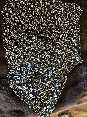 Svart blommig kjol från Newbie - Supersöt svart kjol från Newbie med vitt blommönster. Kjolen har en lätt utsvängd form och resår i midjan för extra komfort. Perfekt för dig som gillar en feminin och trendig stil. Materialet känns mjukt och följsamt.