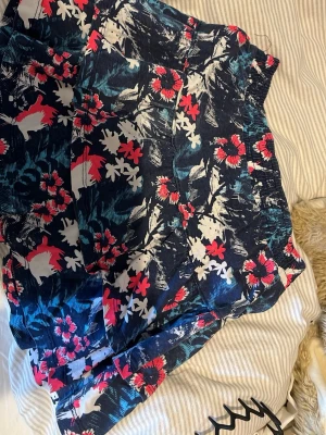 Blommiga shorts från HEMA - Snygga shorts från HEMA med blommigt mönster i blått, vitt och rött. De har en elastisk midja och är perfekta för varma dagar. Lätta och bekväma, passar till många olika stilar.