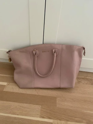 Rosa handväska  - Säljer en väska som jag har haft länge men aldrig använd, köpt från Vinted så den har vissa defekter. Väskan har dragkedja upptill och ett prickigt innerfoder med innerfack och dragkedja. 