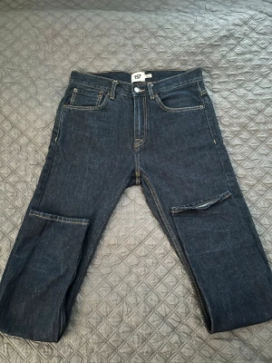 Mörkblå jeans från 157 med cargoficka - Säljer ett par mörkblå jeans från 157 med raka ben och en cool cargoficka på ena benet. Klassisk femficksmodell med kontrastsömmar och patch bak i midjan. Perfekta för dig som gillar streetwear och vill ha något unikt i garderoben. Storlek w30 läng 32