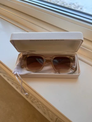 Beige solglasögon från CHIMI - Säljer ett par snygga solglasögon från CHIMI i beige transparent plast med bruna tonade glas. De har en fyrkantig form och kommer i originalfodral. Man ser vilken model och färg det är på bilderna! Använt fåtal gånger! Bara att skriva för funderingar