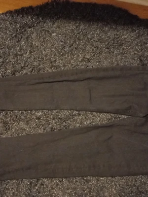 Mörkgrå leggings med smal passform - Snygga mörkgrå leggings med smal passform och stretchigt material. Perfekta för en avslappnad look och enkla att matcha med olika toppar. Inga synliga detaljer eller mönster, bara klassiskt stilrena.