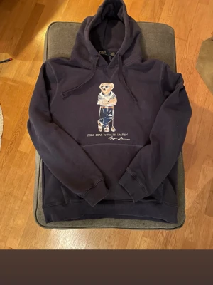 Mörkblå hoodie Polo Bear Ralph Lauren - Snygg mörkblå hoodie från Ralph Lauren med Polo Bear-tryck på bröstet. Färgen är marinblå och den passar M och S. Priset går att diskutera.