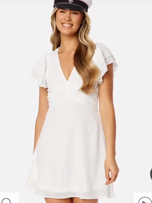 Söt studentklänning - Söt vit kortklänning med v-ringning och volangärmar.Perfekt till studenten! Aldrig använd! Nypris 699kkr!