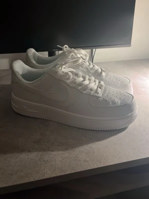 Nike Air Force 1 vita sneakers( pris kan diskuteras) - Klassiska helvita Nike Air Force 1 sneakers i lågt utförande. Skorna har en stilren design med perforerad tå, vita skosnören och Nike-logga på sidan. Tillverkade i läder med en robust gummisula för extra komfort och streetkänsla.