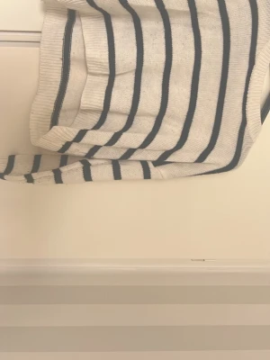 Vit stickad tröja med svarta ränder - Säljer en vit stickad tröja med svarta horisontella ränder. Tröjan har rund halsringning, långa ärmar och ribbade muddar vid ärmslut och nederkant. Perfekt för dig som gillar klassisk och enkel stil.