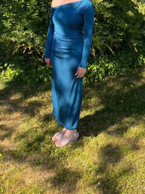 Blå långklänning med oneshoulder - Säljer en elegant blå långklänning med oneshoulder och lång ärm. Klänningen har en smickrande drapering i midjan och är figurnära med en stilren siluett. Perfekt för dig som vill sticka ut med en modern och trendig look. Skriv gärna för fler bilder! Den ligger slutsåld på Zalando bla och heter ”STOCKH LM studio. Venus- Maxiklänning-moroccan blue.”