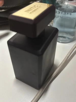 Tom Ford Oud Wood Eau de Parfum - Lyxig parfym från Tom Ford i en elegant, mörkbrun fyrkantig flaska med guldfärgade detaljer och lock. Flaskan har en exklusiv känsla och passar perfekt för dig som gillar exklusiva dofter med träiga inslag.