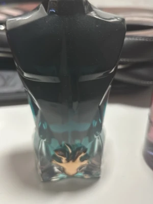 Le Male parfym Jean Paul Gaultier - Ikonisk parfymflaska formad som en manlig torso i blått och svart glas med gulddetalj vid basen. Flaskan har en unik design som verkligen sticker ut på hyllan och är ett måste för dig som gillar klassiska dofter med modern twist.