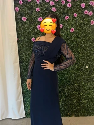 Bröllopsklänning/festklänning - Elegant marinblå långklänning med glittriga detaljer vid ärmarna och brösten. Ingen slitage alls. Säljer pga att den inte kommer komma till användning. Använd endast 1 gång i ca 2h. Köpte för ca 1900kr. Säljer för 1500kr, men pris kan diskuteras. Storlek 38/M men passar även 36/S. Vänligen kontakta mig vid frågor.