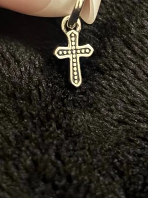 Silver korsberlock från pandora - Pandora korsberlock. Korset har små pärldetaljer längs hela formen som ger en unik och trendig look. Perfekt accessoar för dig som gillar minimalistiska smycken med en twist.