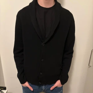 Svart Cardigan - Säljer denna feta svarta cardigan. Människan på bilden är 187 cm. Nytt skick.                                                      Hör av dig om du har nån minsta fråga🤝