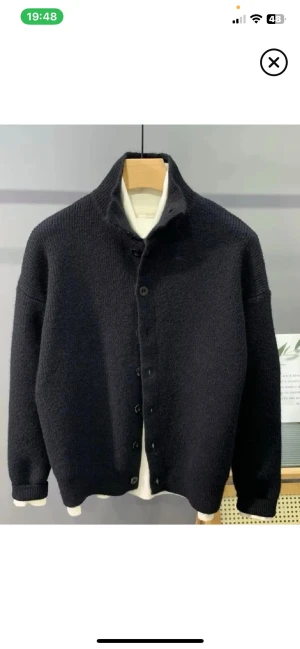 Stickad kofta - Snygg svart stickad kofta med hög krage och knäppning framtill. Koftan har en avslappnad passform, långa ärmar och ribbade muddar. Perfekt för lager på lager och enkel att matcha med olika outfits.