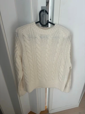 Vit kabelstickad tröja Stand Studio - Säljer en krämvit kabelstickad tröja från Stand Studio. Helt ny och aldrig använd! Så fint material och snygg passform 