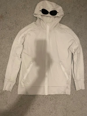 Vit cp company hoddie - Säljer en vit hoodie från C.P. Company med dragkedja framtill och två snedställda fickor med dragkedja. Äkta såklart! Om ni tycker färgen är konstigt så är det för armen har legat på mina nya otvättade jeans men en tvätt i maskinen tar bort(inte första gången). Pris är lite rörligt. Skriv för frågor ! M men passar S också