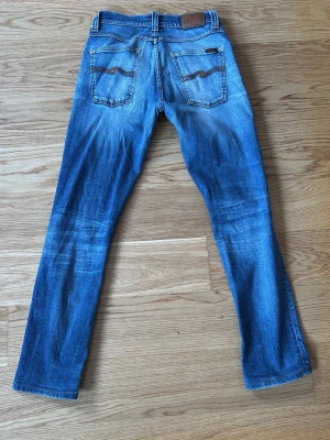 Nudie Jeans Grim Tim - Säljer dessa scyssta jeans med unik användning och professionella lagningar för en snygg sliten look. W31 L32 modell Grim Tim