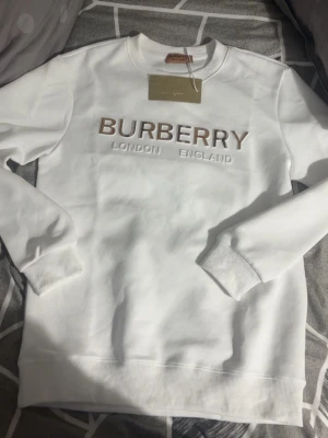 Zara  - Snygg vit sweatshirt  med klassisk rund halsringning och ribbade muddar. Tröjan är enkel och stilren, perfekt för dig som gillar exklusiva märken och minimalistisk design. Materialet känns mjukt och bekvämt mot huden.