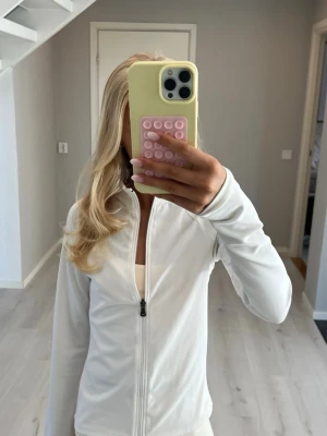 Vit träningsjacka - Superfin vit jacka/tröja med lång ärm och hög krage. Tröjan har dragkedja framtill och är figursydd, perfekt för träning eller yoga. Enkel och stilren design som passar perfekt och går att använda till det mesta. 🤍🤍