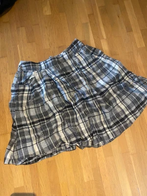 Linnekjol - Säljer en svartvit rutig linnekjol från Lindex i storlek 36. Kjolen har fickor fram och dragkedja bak.  100% lin