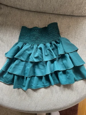 Mörkgrön volangkjol  - Jättefin mörkgrön minikjol med volanger från second hand i storlek one size (men passar storlek S). Är oanvänd och i väldigt bra skick💓